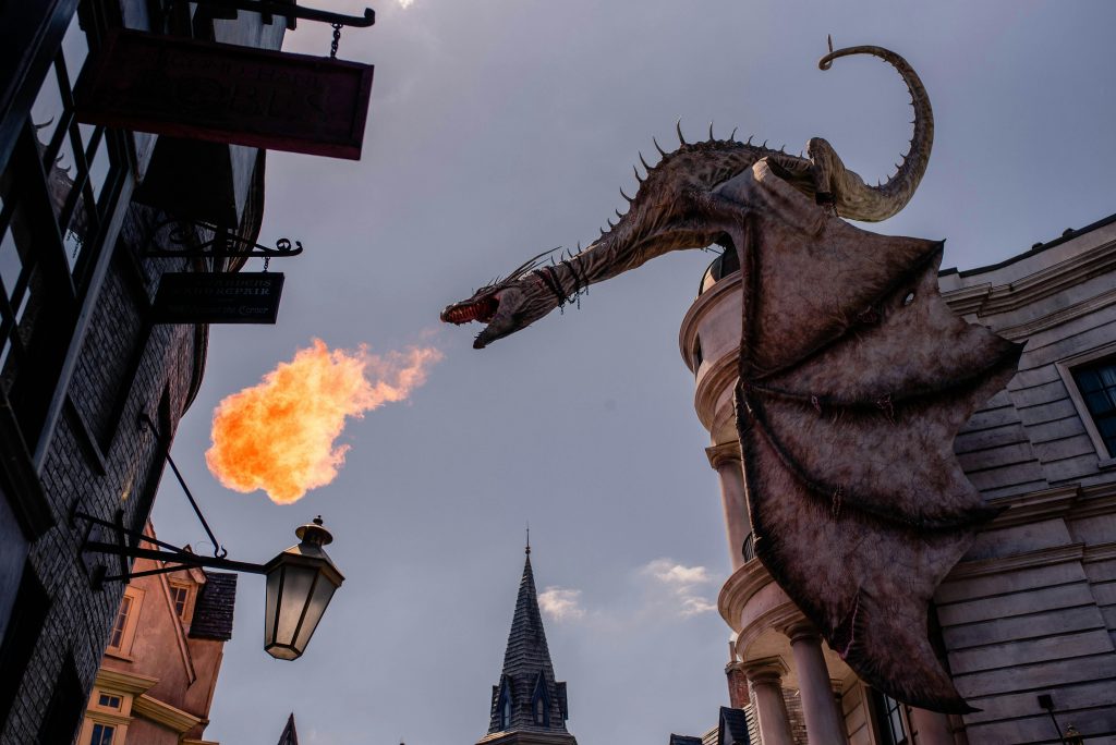 Fire-breathing dragon perched atop Gringotts Bank at Universal Studios’ Diagon Alley, roaring flames into the sky.